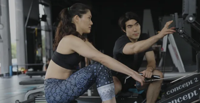 A BASE Bangkok trainer coaching a client on a rowing machine