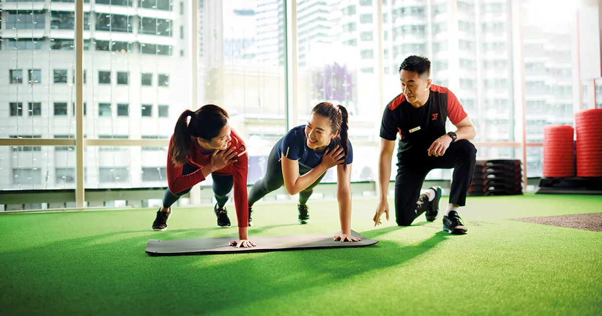 A Fitness First trainer coaching two members